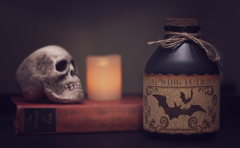 Healthier Halloween Cocktails A Jug of Poison on a Table Next to a Candle and a Skull