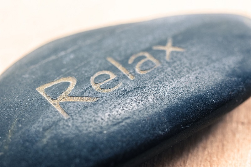 Passive Income Made Easy a Rock With the Word "Relax" Carved Into it