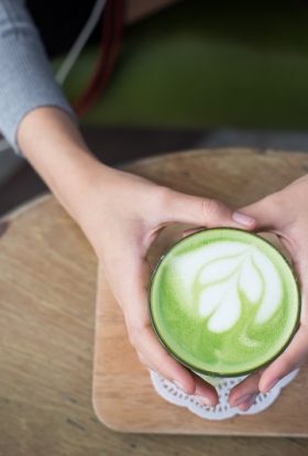 Energy Boosting Tea Recipes Overhead View of a Person Holding a Cup of Green Matcha Tea